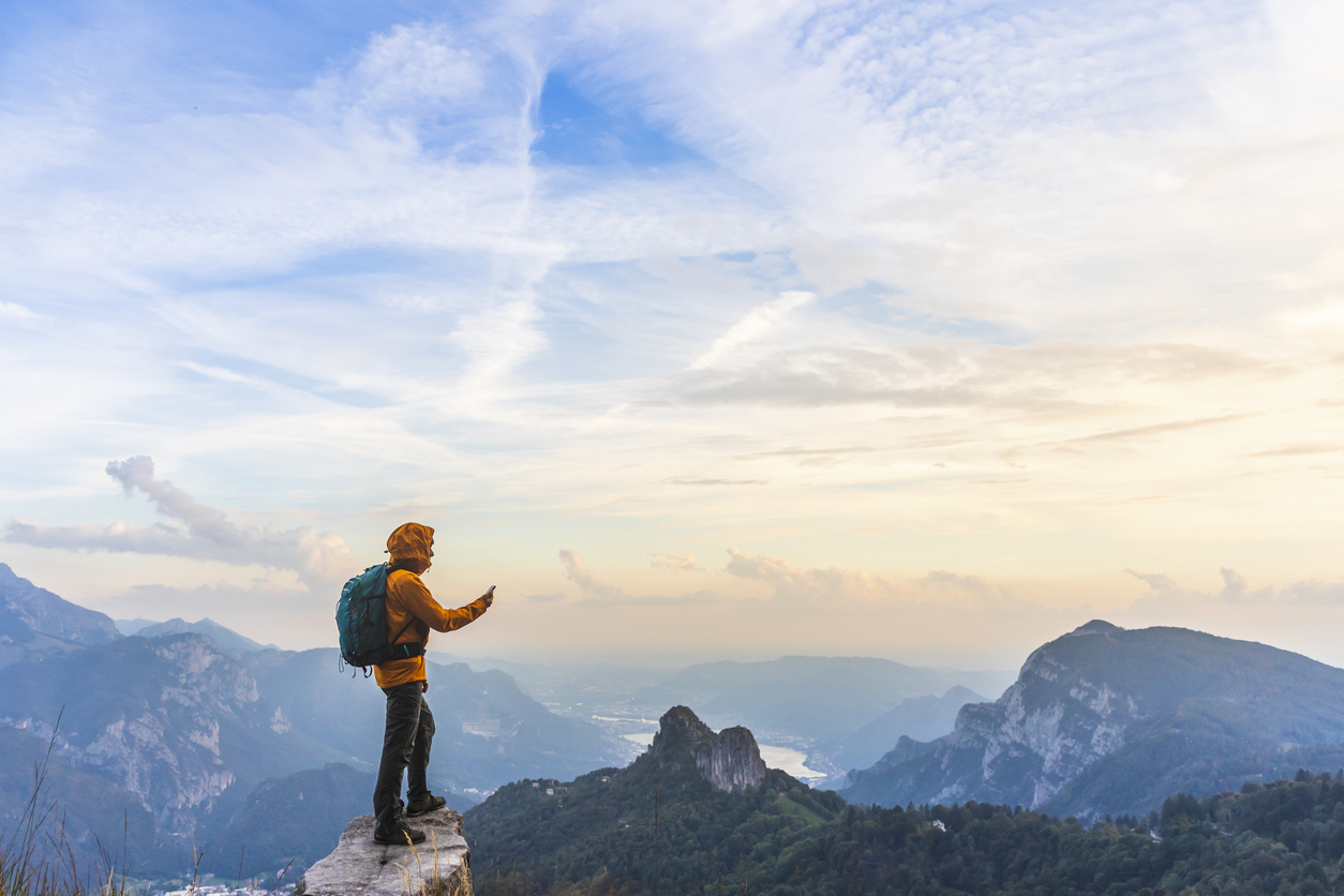 hiker on summit with smartphone in hand