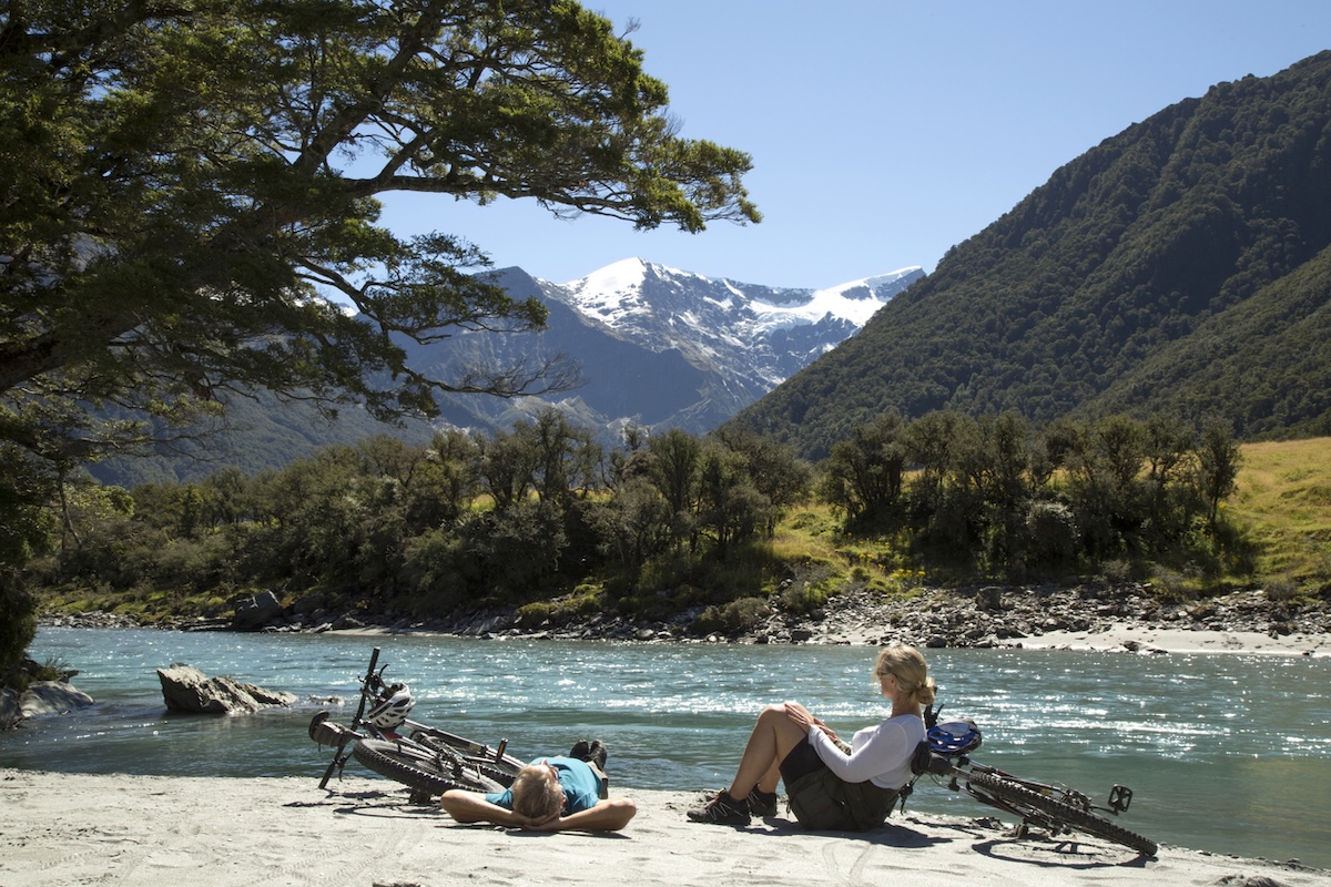 couple-by-a-river-with-mountain-bikes-new-zealand