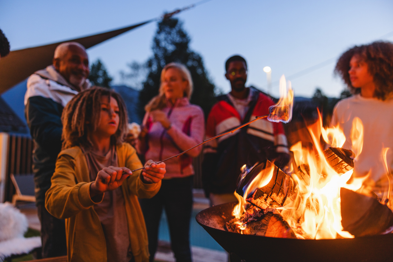 Multigenerational-Mixed-Race-Family-Enjoying-a-Campfire-Outdoors-at-Dusk