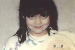 Smiling Alie Berrelez holding a stuffed toy