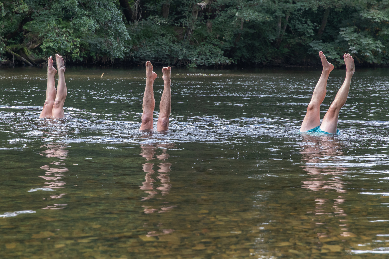 Three-pairs-of-legs-stick-out-from-the-river-water