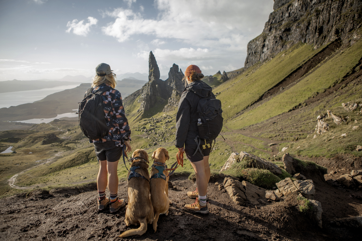 Two-female-hikers-walking-on-the-isle-of-skye-Scotland-with-their-dogs