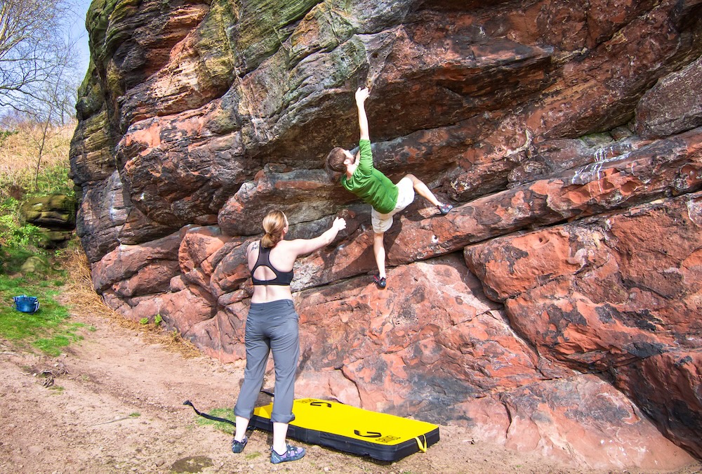 Woman spotting a man bouldering