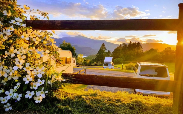 campers parked with flowers in foreground and mountains and sunset in background lake district campsites credit castlerigg hall