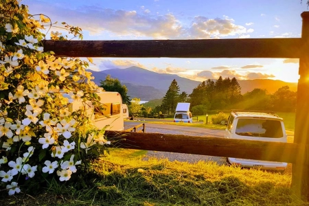 campers parked with flowers in foreground and mountains and sunset in background lake district campsites credit castlerigg hall