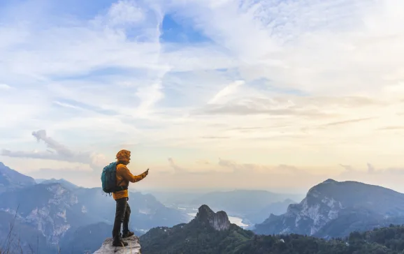 hiker on summit with smartphone in hand