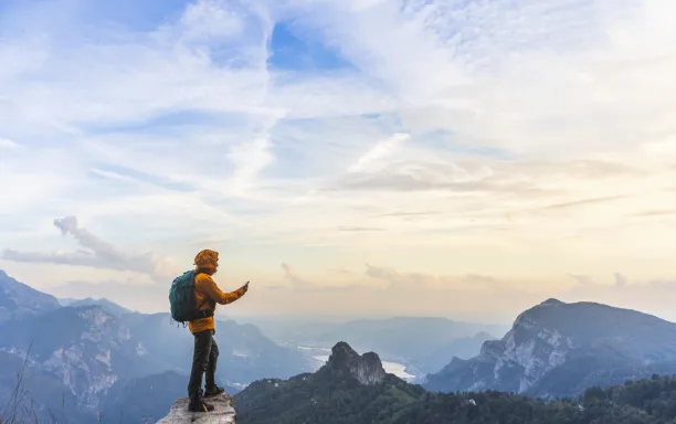 hiker on summit with smartphone in hand