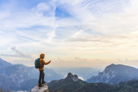 hiker on summit with smartphone in hand