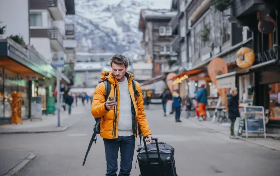 man with duffle bag in alpine village